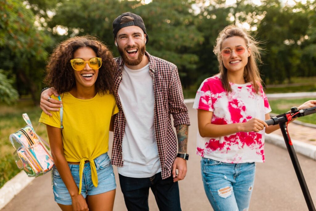 happy-young-company-smiling-friends-walking-park-with-electric-kick-scooter-man-women-having-fun-together
